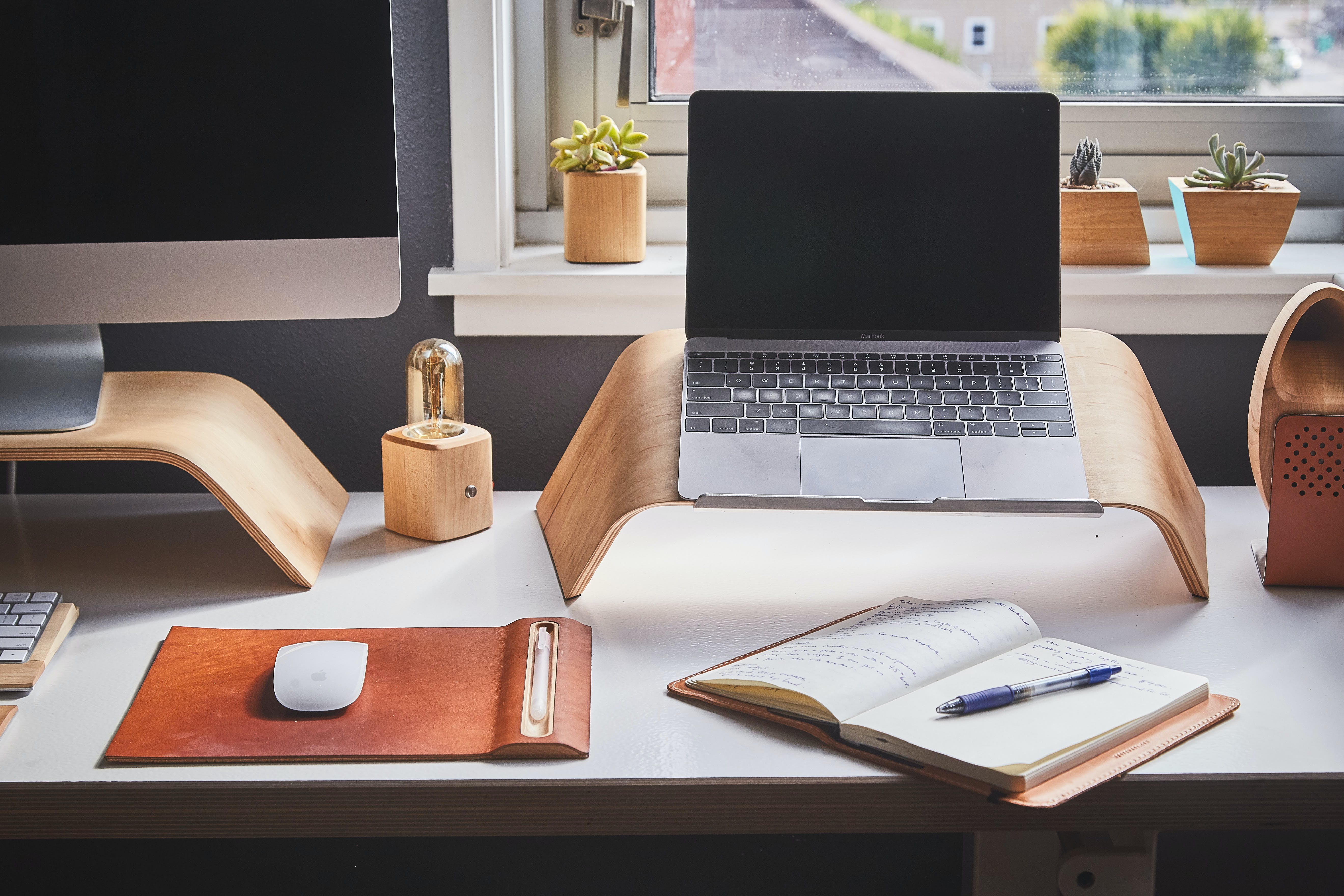 desktop and laptop computers with pen and book on table