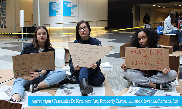 students sitting with homeless signs